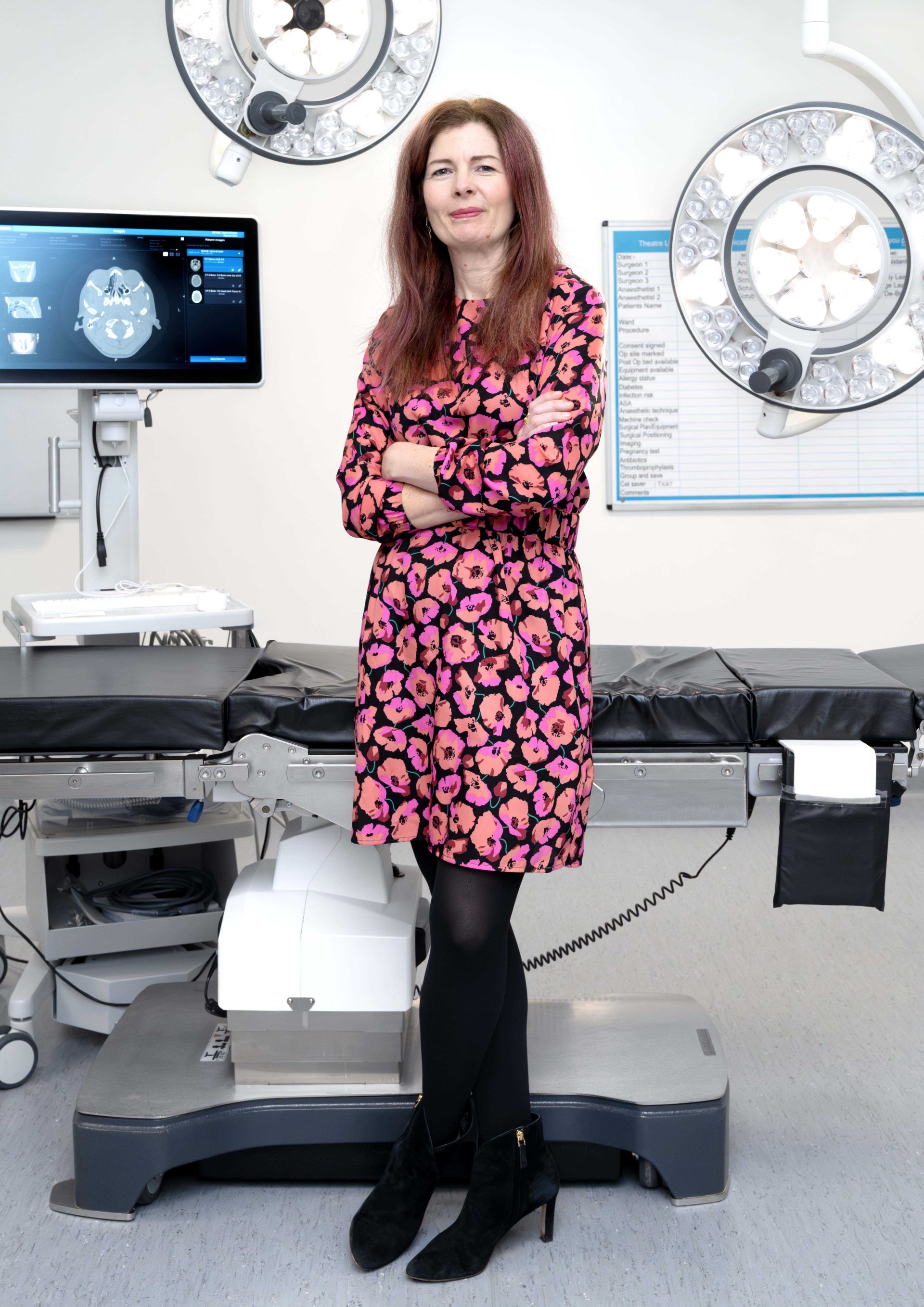 Individual in a pink and black dress, standing in a surgical theatre