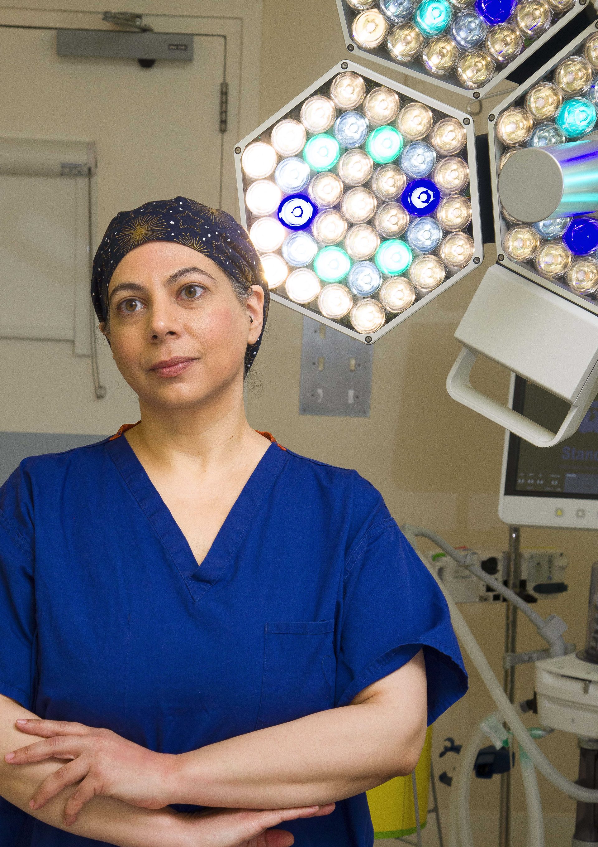 Individual in dark blue scrubs, standing in a surgical theatre