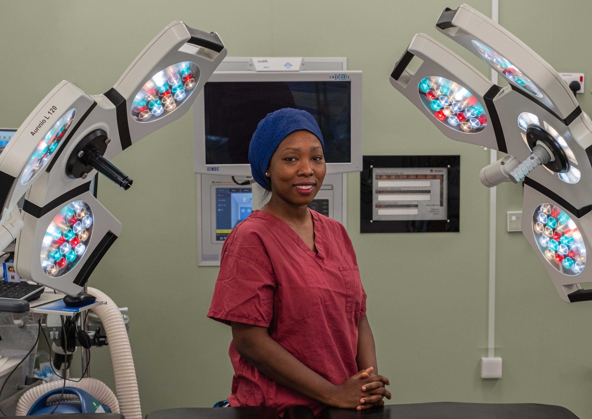 Individual in light red scrubs, standing in surgical theatre