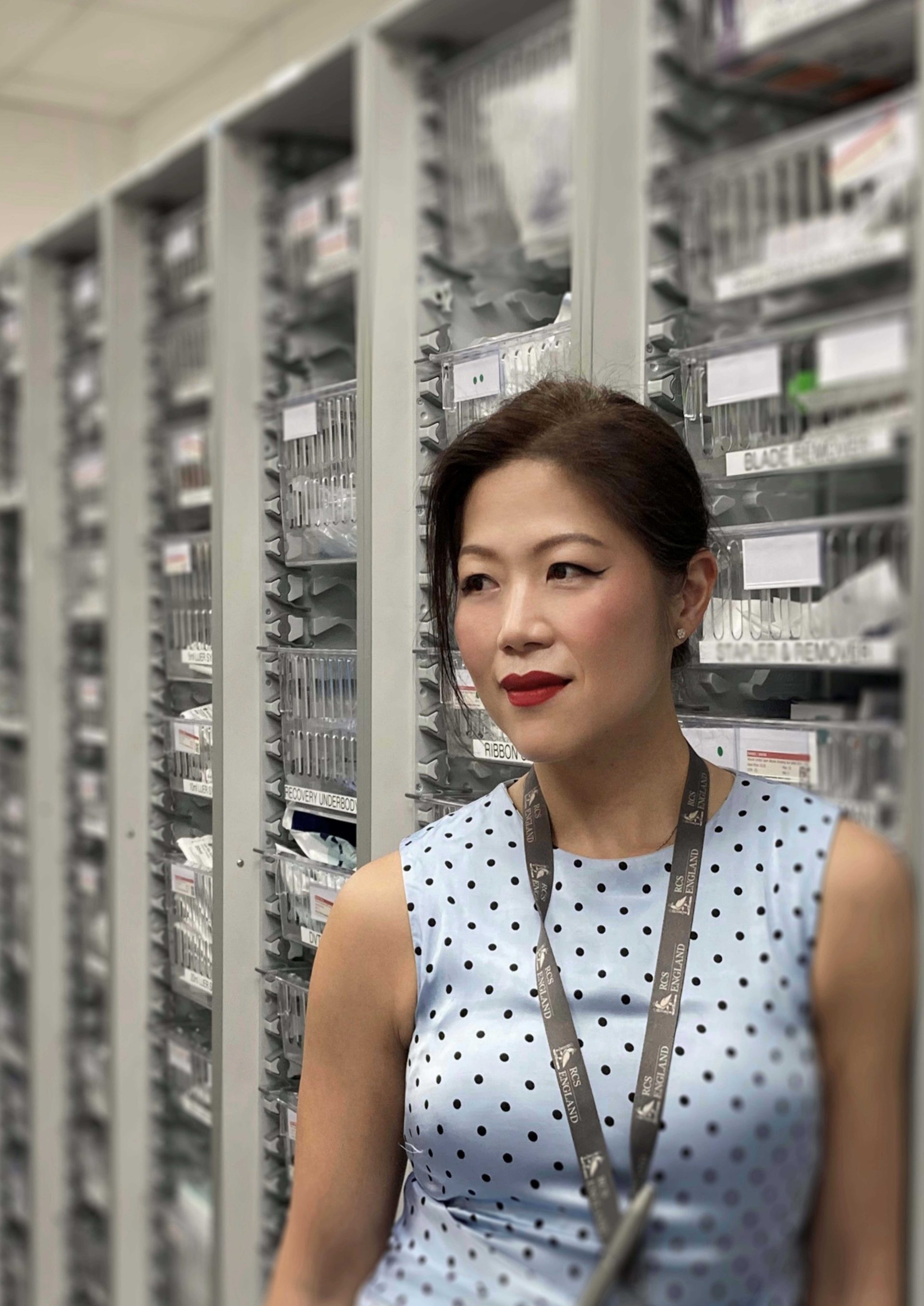 Individual a blue spotted top in a clinical room filled with shelves
