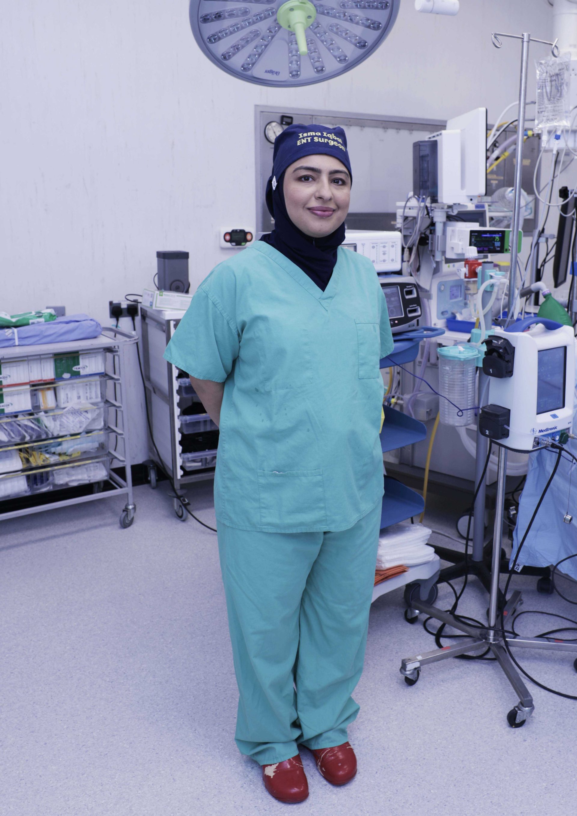 Individual wearing green scrubs and red clogs in a surgical theatre