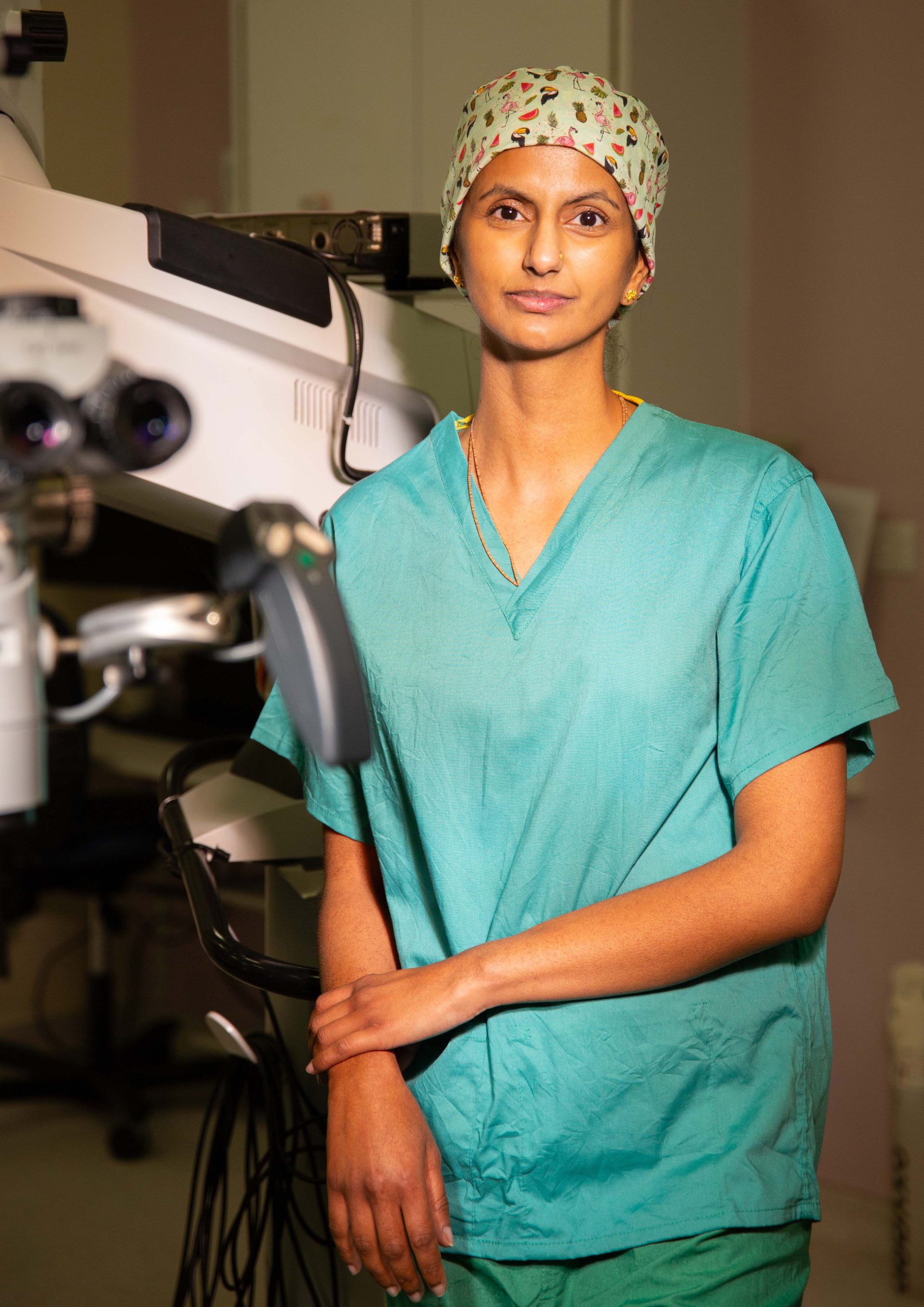 Individual wearing green scrubs standing in a clinical room