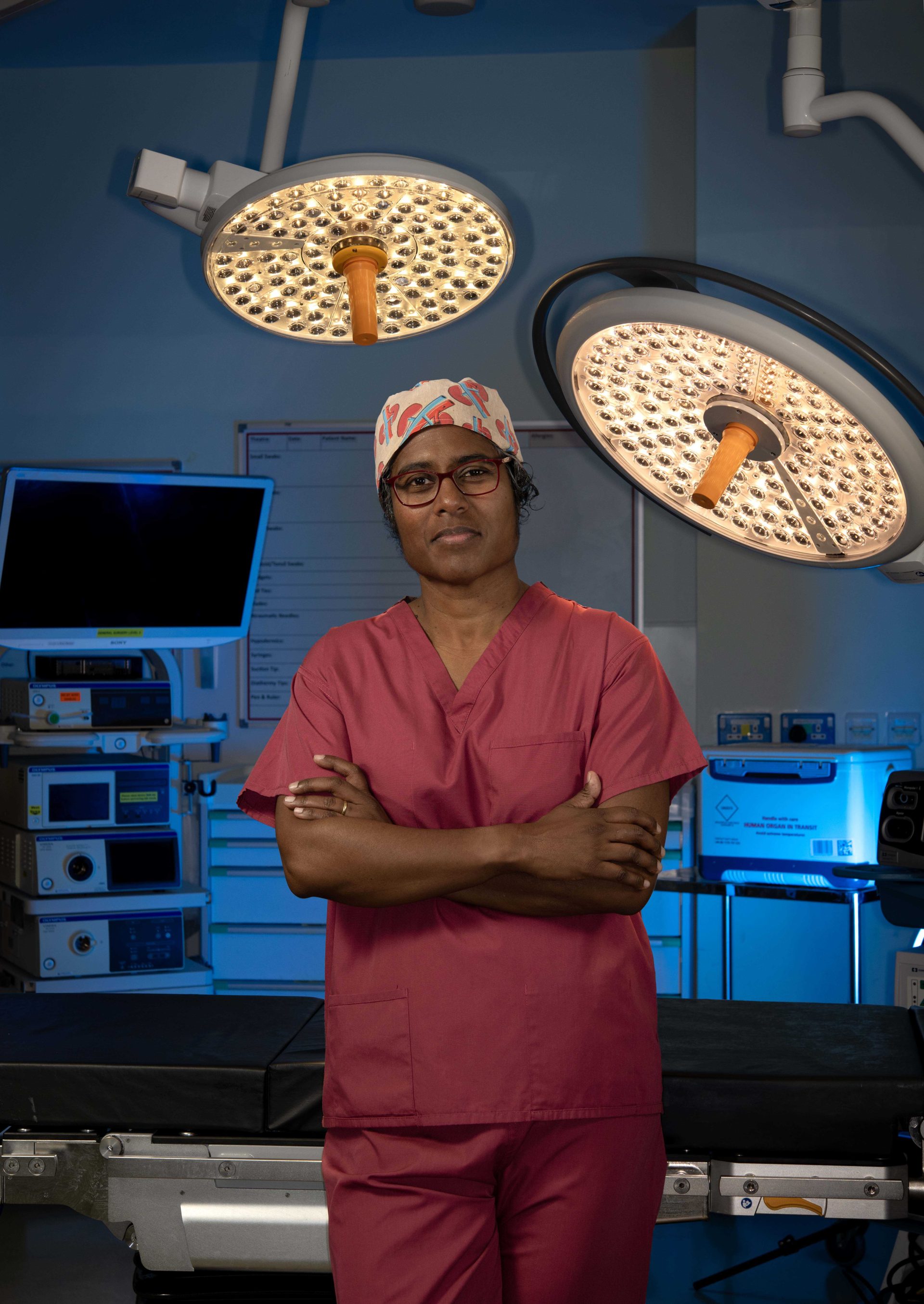 Individual in light red scrubs, standing in surgical theatre