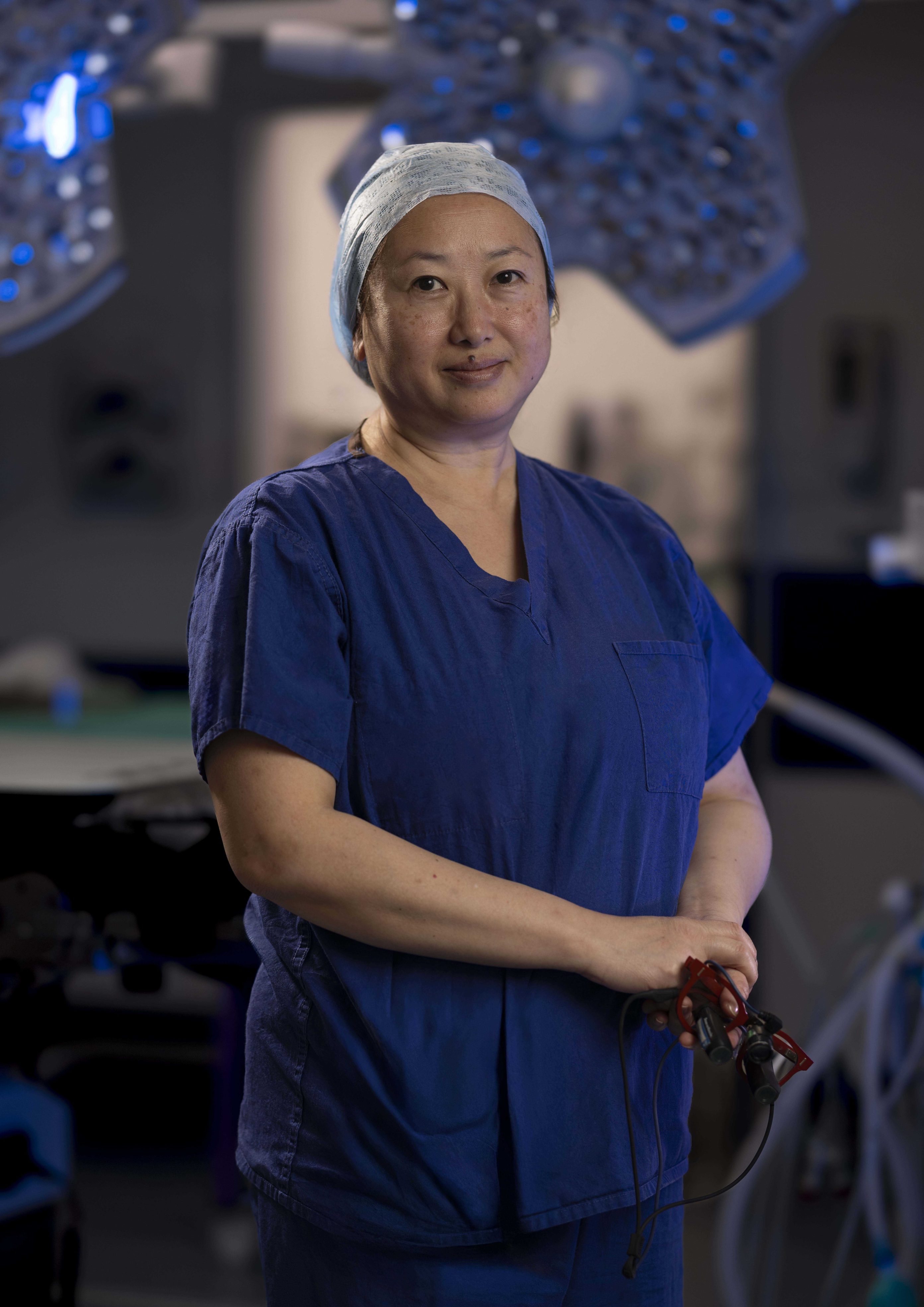 Individual in dark blue scrubs, standing in a surgical theatre